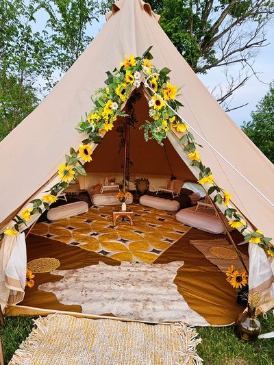 Sunflower-themed luxury outdoor bell tent setup with styled twin mattress glamping experience