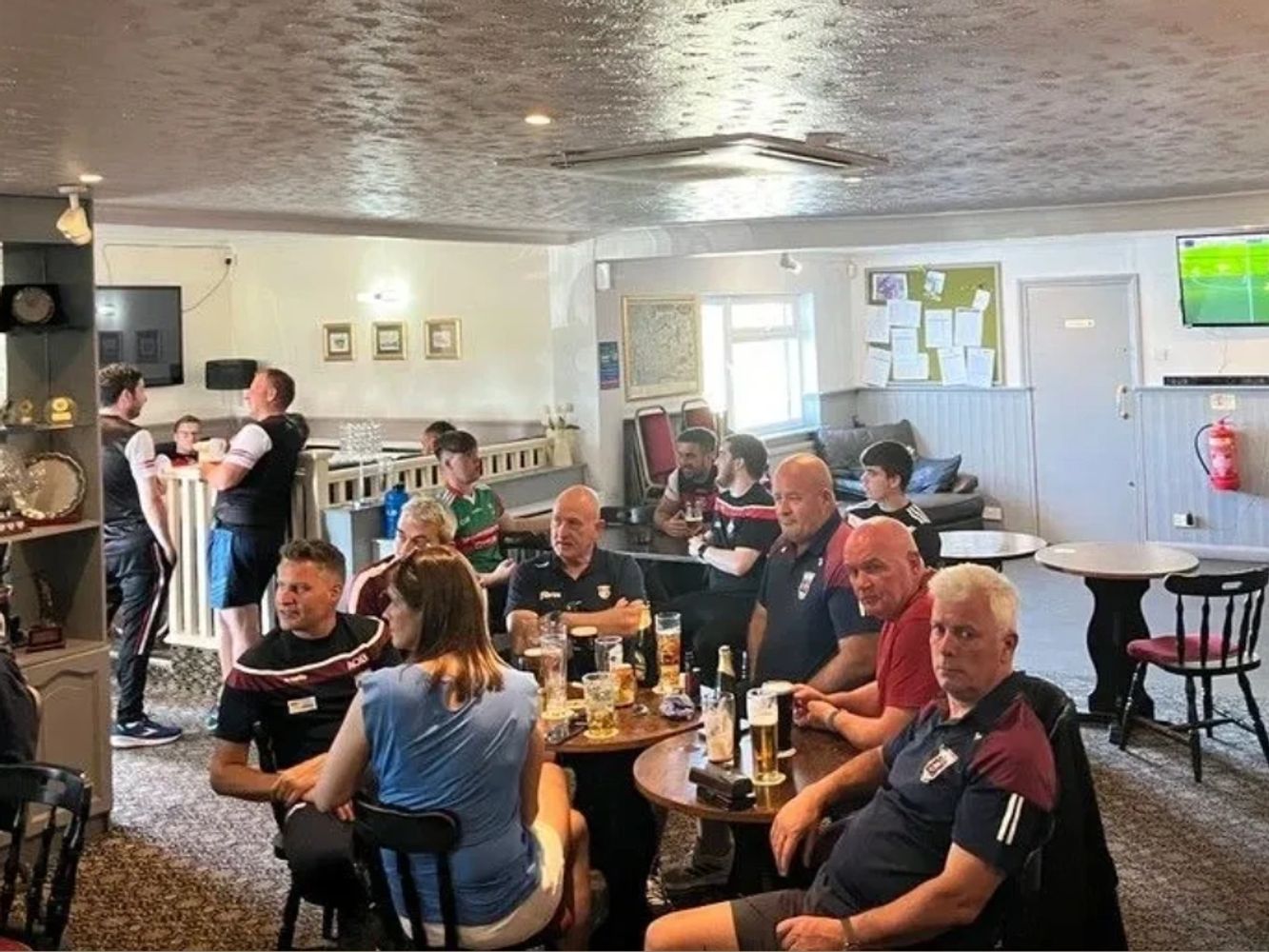 Group of people in the Irish Club having a drink together and watching the GAA on TV.