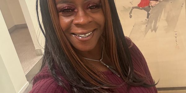 Smiling woman in a maroon sweater taking a selfie indoors.
