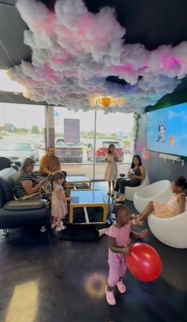 Kids and adults playing in a colorful indoor space with a cloud ceiling.