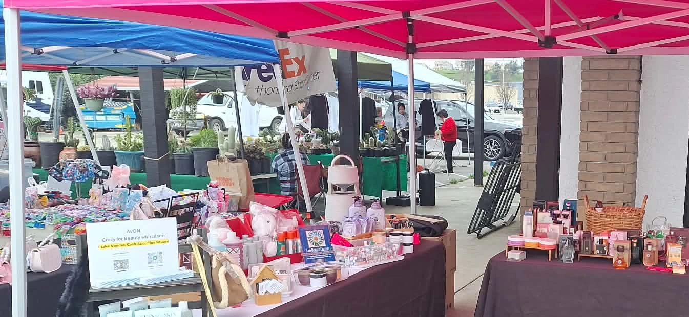 Outdoor market stalls with beauty products and handmade items under colorful canopies.