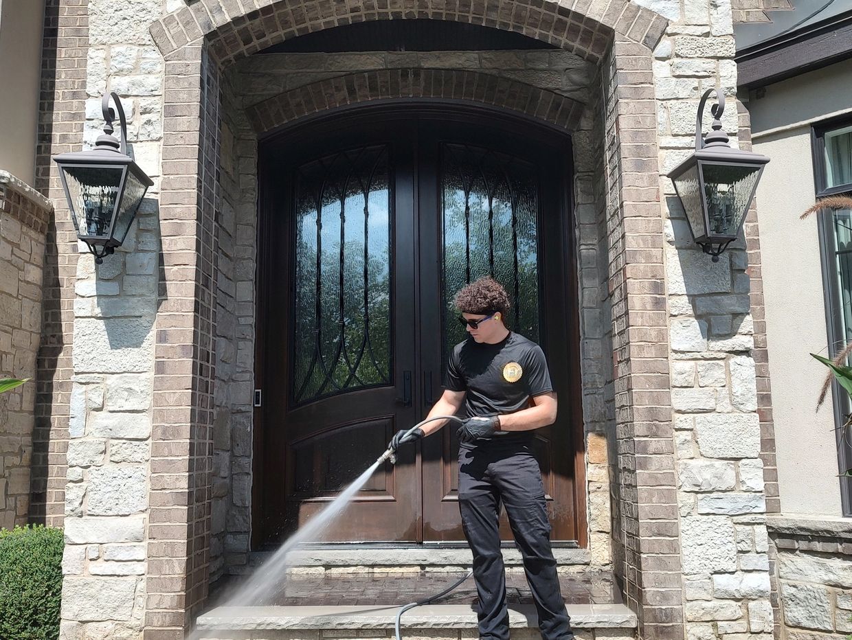 Man pressure washing front steps of a house.