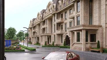 Elegant beige stone apartment complex with cars and greenery.
