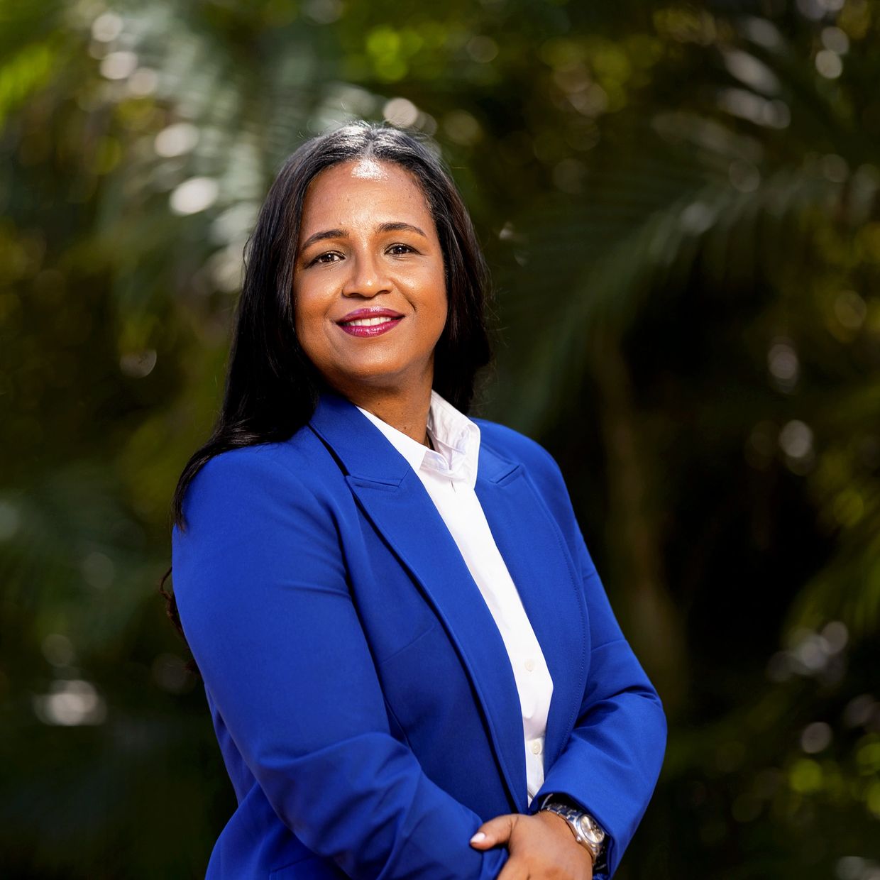 Confident woman in a blue blazer smiling outdoors.