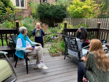 Four people engaged in conversation on a wooden deck.