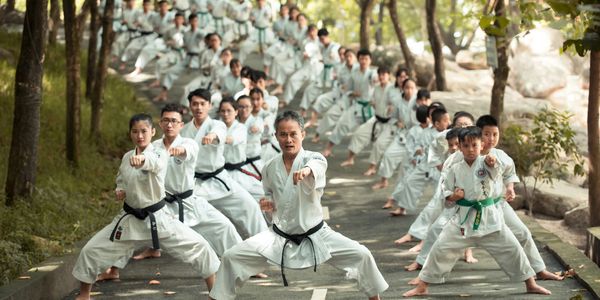 Large group practicing karate outdoors in uniform.