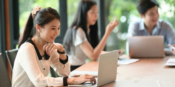 Young woman working on a laptop in a collaborative workspace.