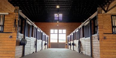 Interior of a well-maintained horse stable with wooden stalls and natural light.