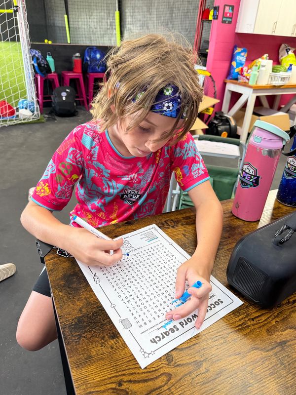 Child solving a word search puzzle at a table.