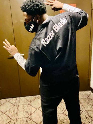 Person in black outfit with 'Razor Blade' text on back making hand gestures.