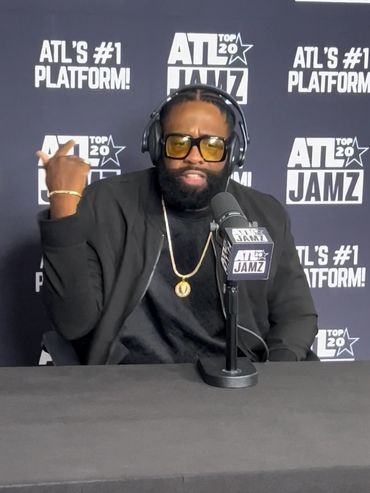 Man wearing headphones speaking into ATL Jamz microphone at podcast.