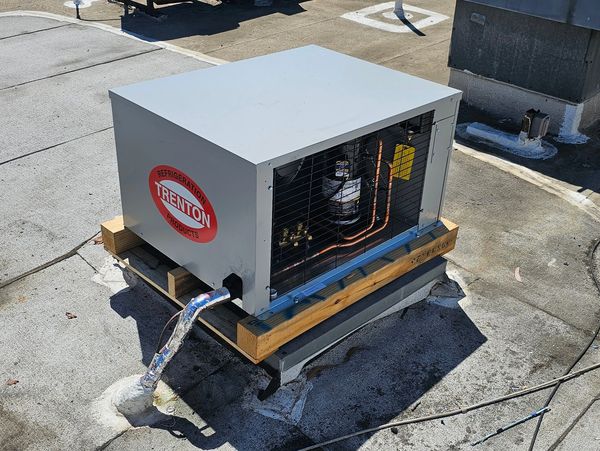 A rooftop refrigeration unit labeled 'Trenton' with exposed copper piping.