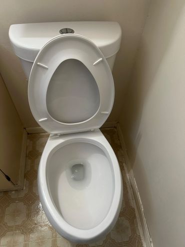 Clean white toilet with open lid and beige patterned floor.