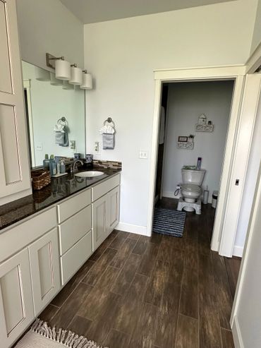 Modern bathroom with wooden floor and white cabinets.