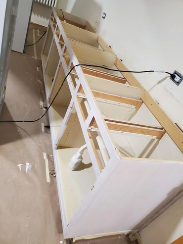 Partially assembled kitchen cabinets without doors, in a room under renovation.