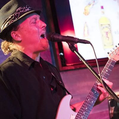 Man passionately playing guitar and singing on stage.