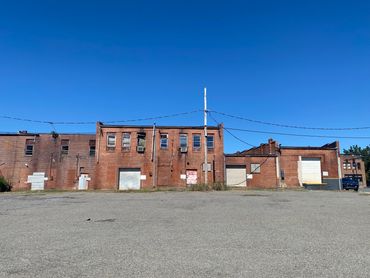 Old red brick industrial buildings under a clear blue sky.