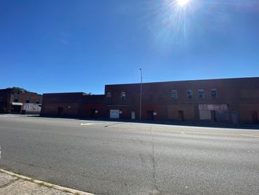 A sunny day with clear blue skies over a large brick building and empty street.