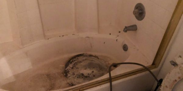 Dirty bathtub with grime and mold buildup.