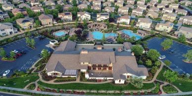 Aerial view of a suburban community clubhouse surrounded by houses and pools.