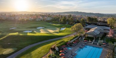 A golf course with a swimming pool and clubhouse at sunset.