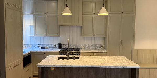 Modern kitchen with marble countertops and pendant lights.