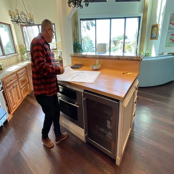 Man reading papers in a kitchen with wooden floors.