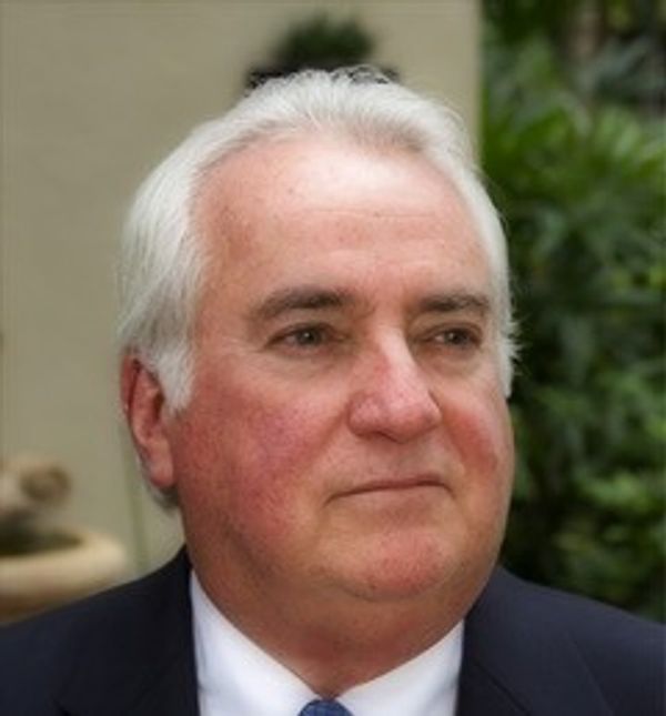 Portrait of an older man with white hair in a suit.