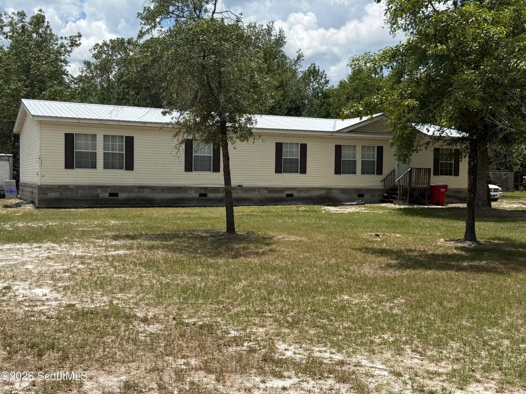 Single-story beige house with dark shutters and a spacious front yard.