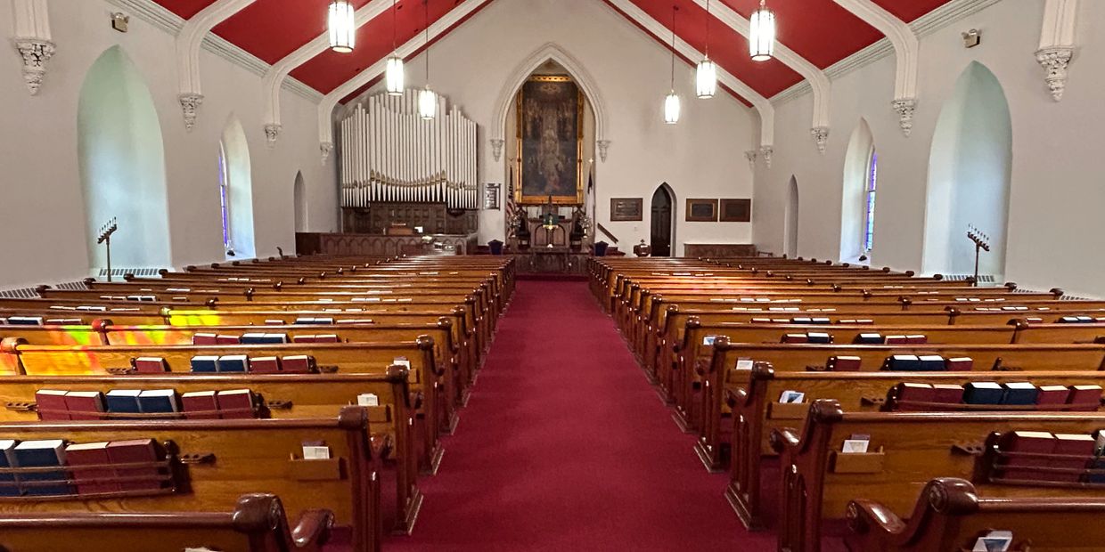 Interior of a church with wooden pews and red carpet.