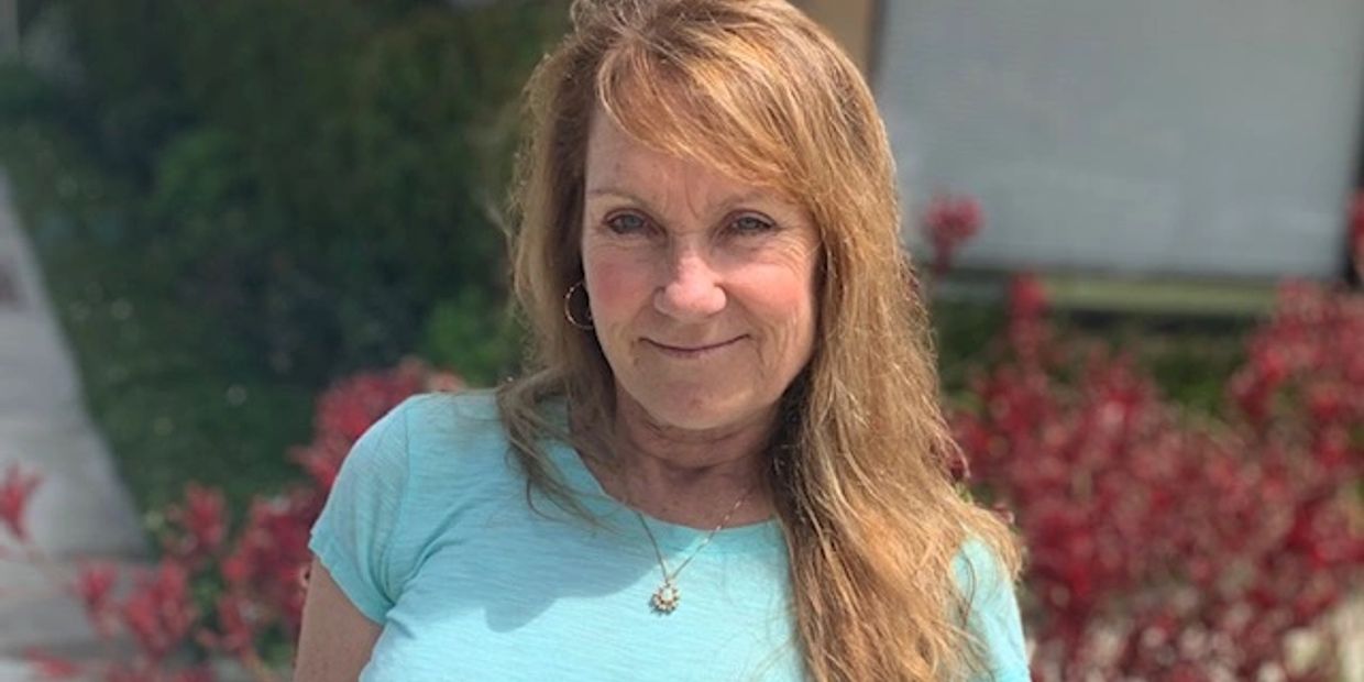 A smiling woman with long strawberry blonde hair in a blue top.