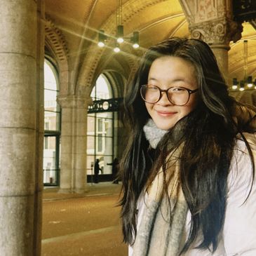 Young woman smiling in a grand, historic building with arches.