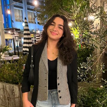 Young woman smiling outdoors at night with stylish outfit.
