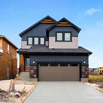 Modern two-story house with a fresh concrete driveway and dark exterior colors.
