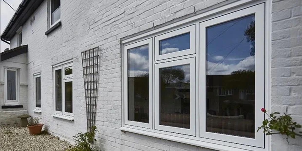 Modern white framed windows on a white brick wall reflecting the sky.