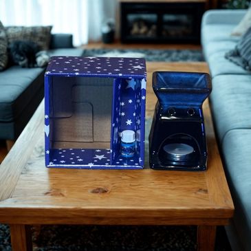 A tea candle warmer and a starry cardboard box on a wooden table.