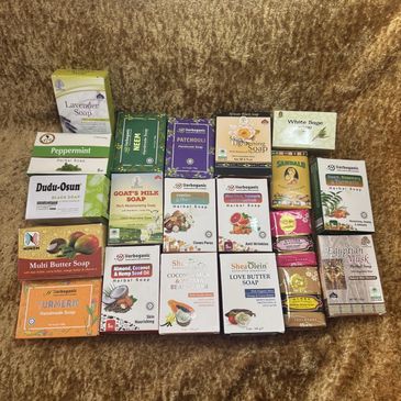 A diverse collection of various herbal and handmade soap bars arranged on a brown textured surface.