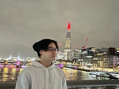 Person standing on a bridge with city lights at night.