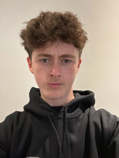 Young man with curly hair wearing a black hoodie.
