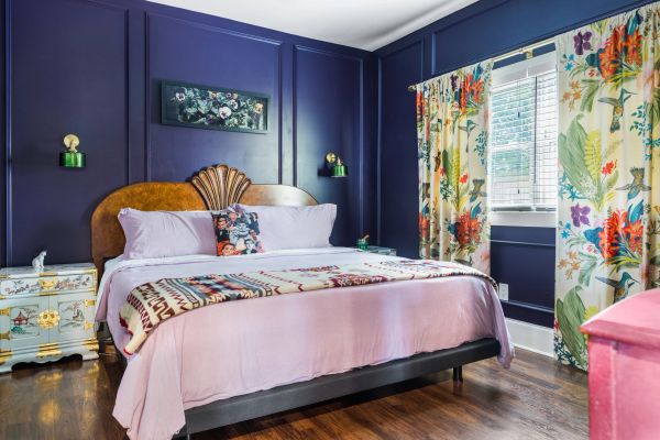Cozy bedroom with floral curtains and dark blue walls.