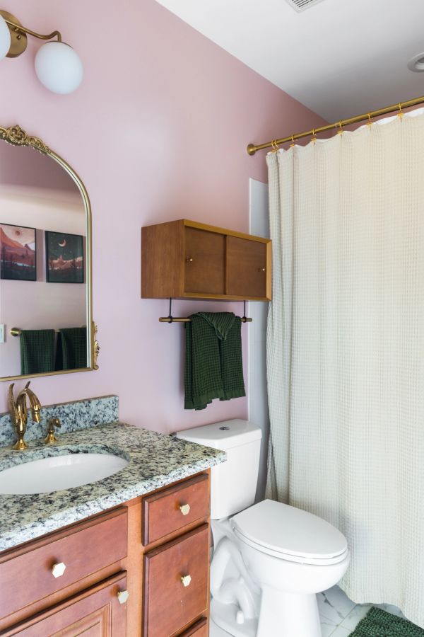 Cozy bathroom with pink walls and granite countertop.