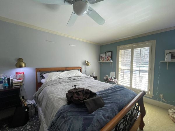 Cozy bedroom with wooden bed frame and natural light from window.
