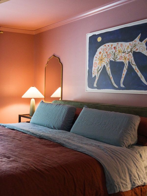 Cozy bedroom with warm lighting, blue bedding, and artistic animal wall art.