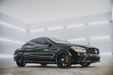 Sleek black Mercedes coupe in a modern white showroom.