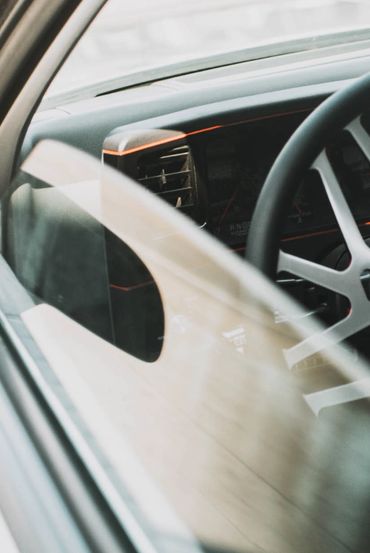 Close-up of a car's interior showing the steering wheel and dashboard through the window.