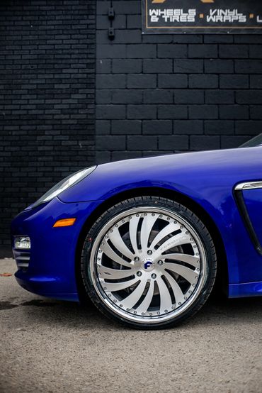 Close-up of a blue sports car's stylish front wheel and tire.