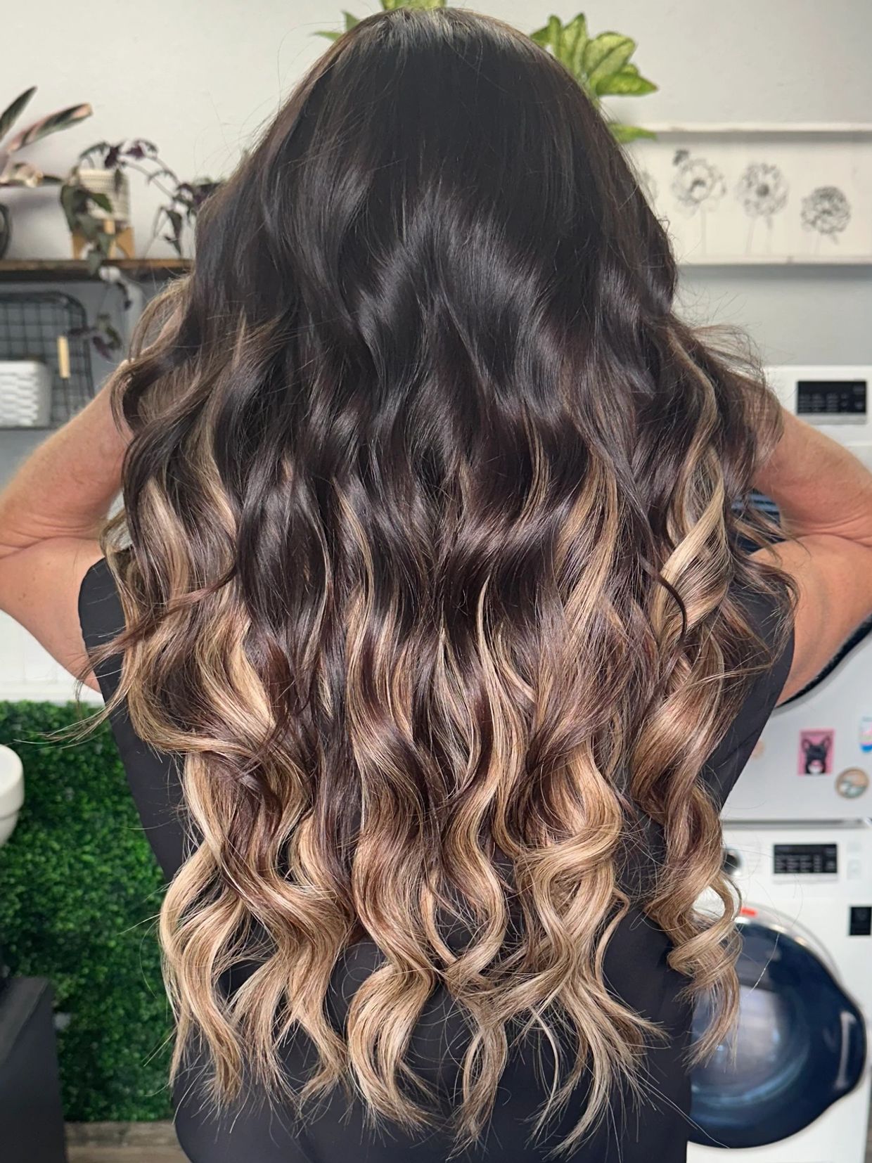 Long wavy hair with dark roots and blonde highlights cascading down.
