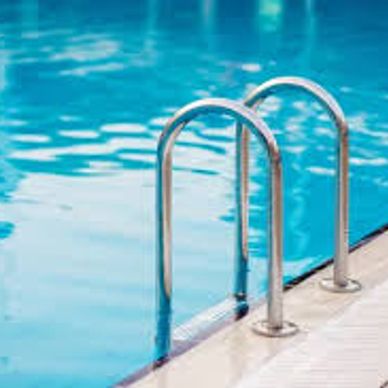 Metal ladder leading into a clear blue swimming pool.