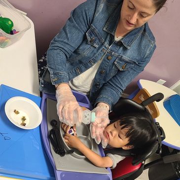 Woman feeding child with bottle in wheelchair.