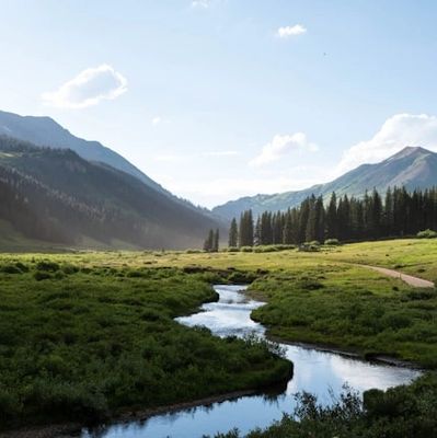 A peaceful mountain valley with a winding river under a clear sky.